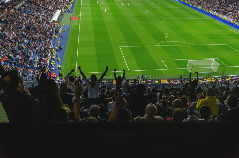 スタジアムでサッカー観戦するサポーターたち